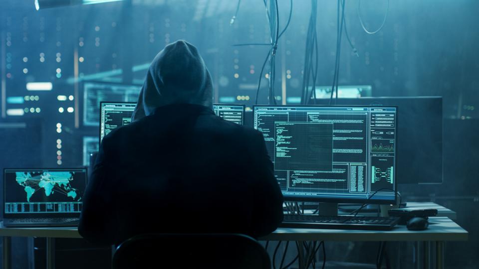 Hooded hacker cyber hacking at a computer screen.
