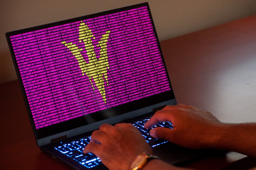 A person types on computer with an illustration of the pitchfork in binary code
