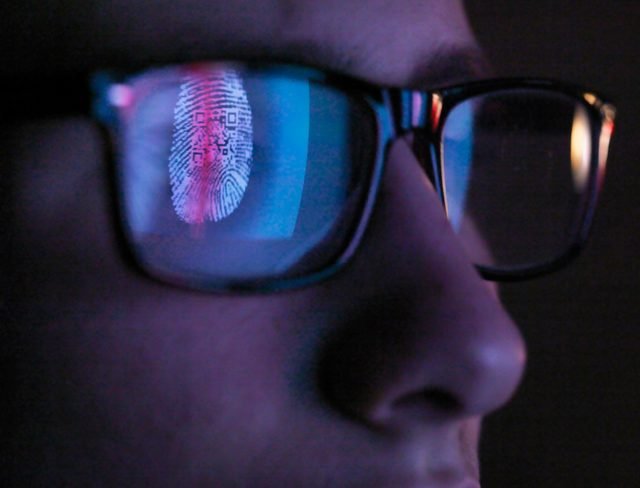 Cyber Security, reflection in spectacles of access information being scanned on computer screen, close up of face