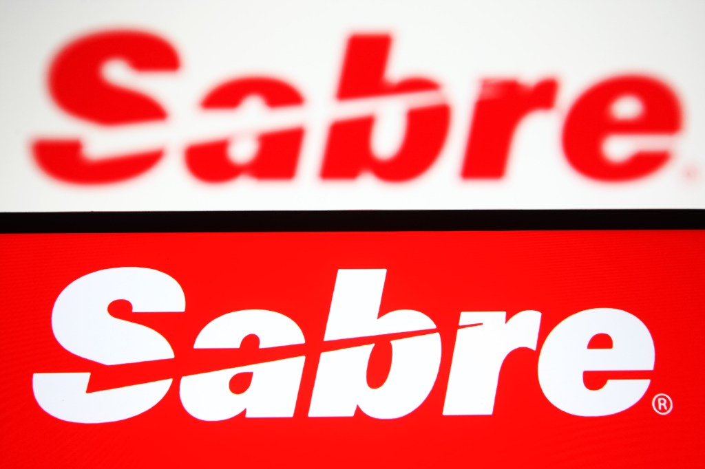 In this photo illustration, Sabre Corporation logo of a travel technology company is seen on a smartphone and a pc screen.